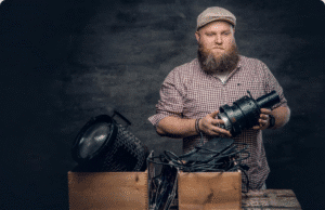 Vyro misija: kaip atrasti savo „sąmoningą dharmą“ ir pajusti tikrą pilnatvę trisdešimtmetis vyras laiko rankose kamerą