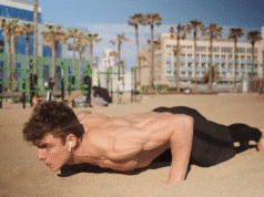 7 fitneso mitai, kuriais vis dar tikite (ir kurie tyliai griauna jūsų pastangas) jaunas vyras paplūdimyje daro atsispaudimus