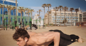 7 fitneso mitai, kuriais vis dar tikite (ir kurie tyliai griauna jūsų pastangas) jaunas vyras paplūdimyje daro atsispaudimus