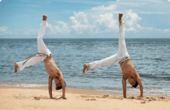 Kapoeira: Brazilijos menas, kuriame telpa šokis, kova ir laisvės istorija du jauni vyrai treniruojasi capoeira