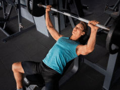 Nuo „vėplos“ iki atleto: Minimalistinė raumenų programa pagal Tim Ferriss vyras treniruojasi sporto salėje su štanga