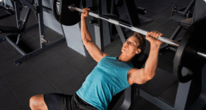 Nuo „vėplos“ iki atleto: Minimalistinė raumenų programa pagal Tim Ferriss vyras treniruojasi sporto salėje su štanga