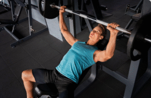 Nuo „vėplos“ iki atleto: Minimalistinė raumenų programa pagal Tim Ferriss vyras treniruojasi sporto salėje su štanga