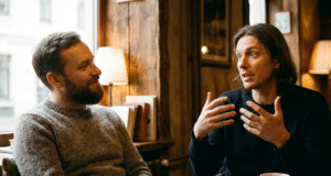 Veidrodžio principas: kaip paprastas atkartojimas padeda užmegzti ryšį? du vyrai kalbasi kavinėje, vienas gestikuliuoja ir pasakoja kitam