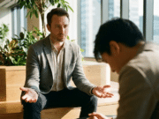 Emocijų įvardijimas: kodėl derybose „ne“ yra vertingesnis už „taip“? du vyrai kalbasi ofise, vienas sėdi nuleidęs galvą