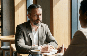 Derybų menas: kaip pasiekti savo tikslų be agresyvios konfrontacijos? vyras kavinėje kalbasi su partneriu ir derasi