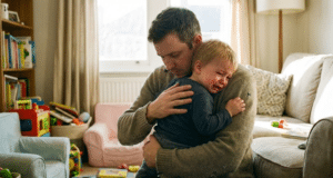 Kaip suvaldyti vaiko emocijas: Inžinieriaus gidas tėvams tėtis apkabinęs ramina savo verkiantį vaiką