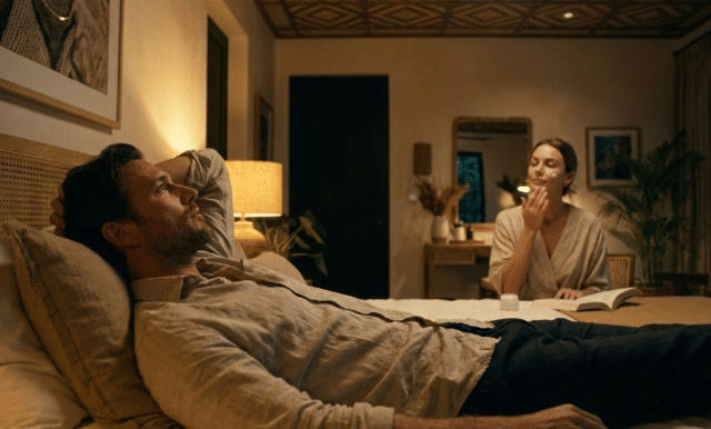 vyras guli lovoje, moteris atlieka vakarinį veido priežiūros ritualą